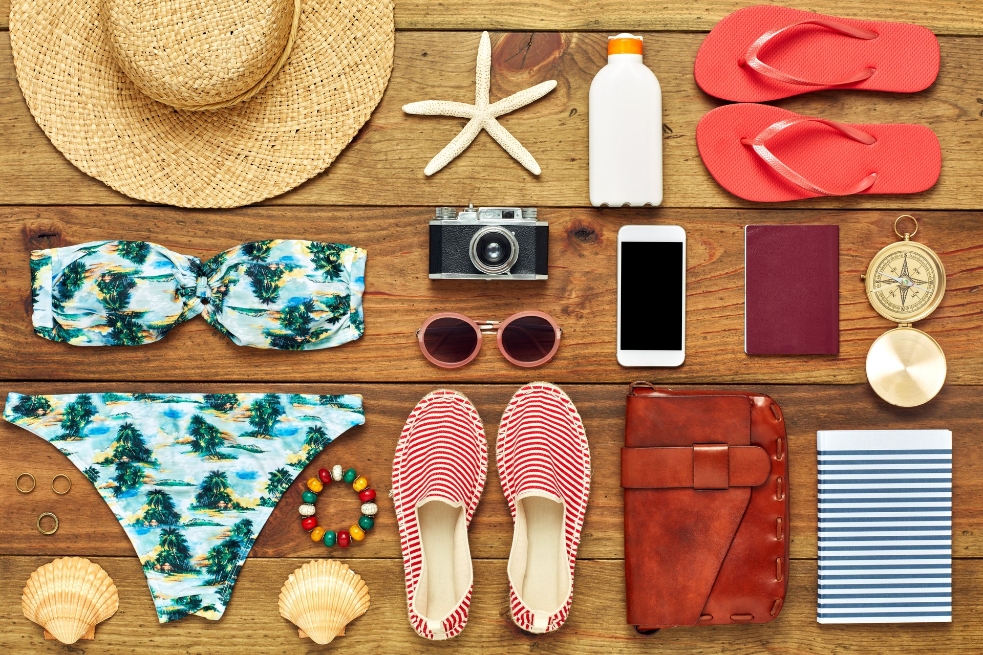 Flat lay of travel and beach accessories on wood