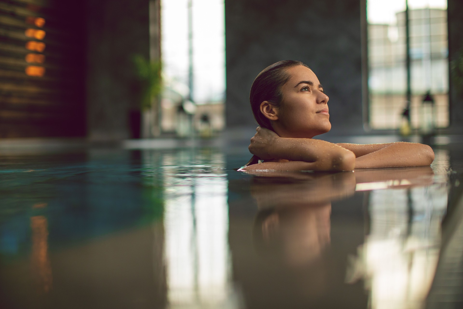 Beautiful young woman relaxing on indoors poolside